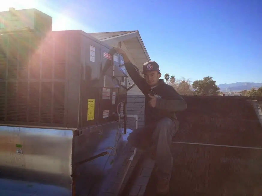 HVAC technician performing Air Duct Cleaning on a rooftop unit in Colchester